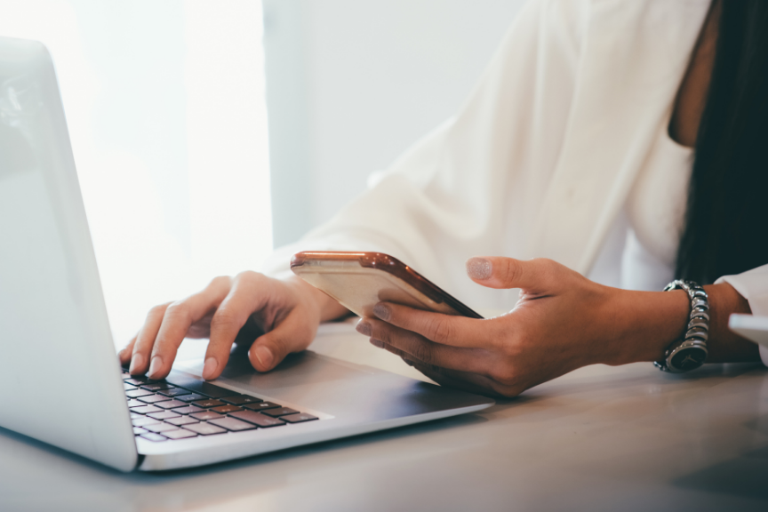 Virtual assistant researching Google Business Profile verification on a laptop while coordinating tasks on a smartphone.